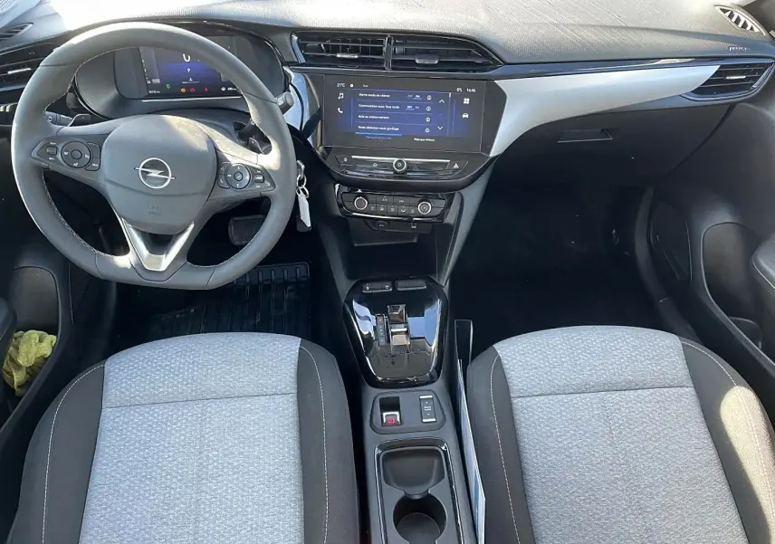Vue intérieure avant de l’Opel Corsa 1.2 turbo 2025 avec tableau de bord noir, écran tactile et sièges tissu gris clair.