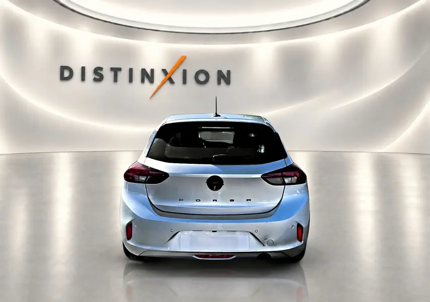 Vue arrière d'une Opel Corsa gris alu 2025 dans un showroom avec logo Distinxion en arrière-plan.