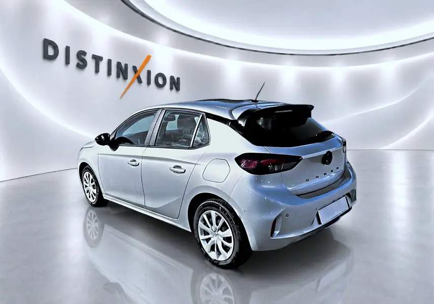 Vue 3/4 arrière droite de l'Opel Corsa 2025 gris alu avec becquet noir et feux arrière foncés dans un showroom lumineux.