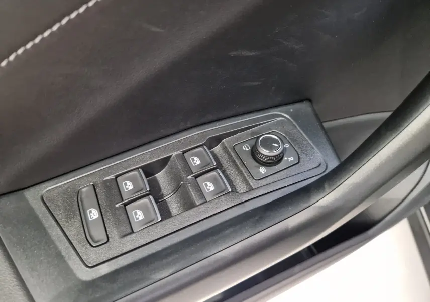 Commande des vitres électriques et réglage des rétroviseurs sur la porte côté conducteur du Volkswagen T-Roc gris indium.