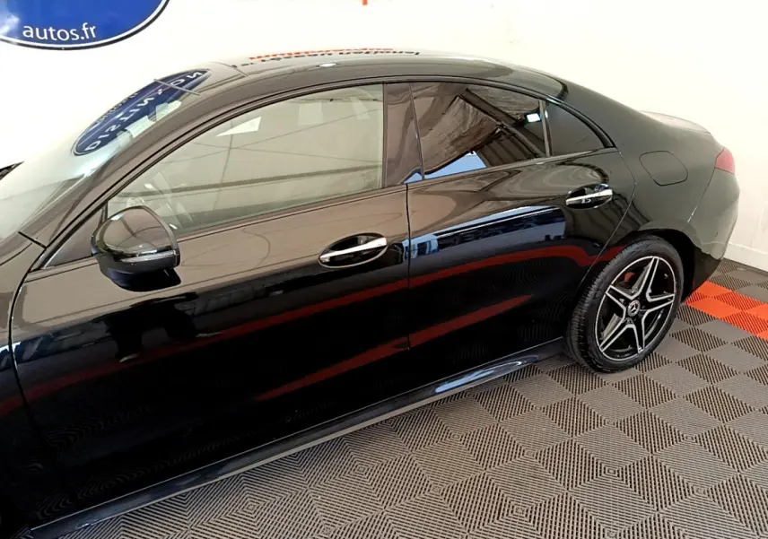 Profil côté gauche d'une Mercedes CLA 200 d AMG Line noire, avec jantes étoile et vitres teintées dans un showroom.