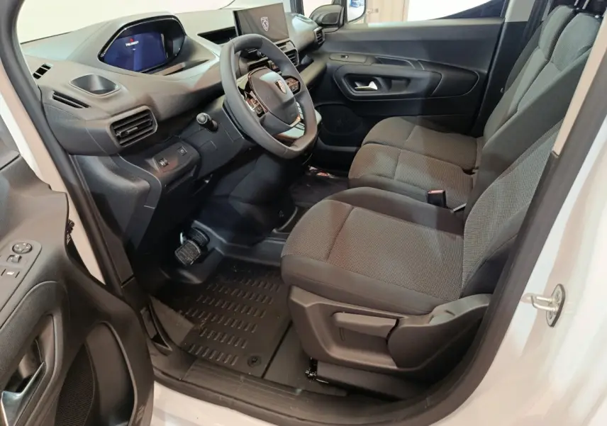 Vue intérieure côté conducteur du Peugeot Partner blanc 2025, montrant sièges tissu gris et tableau de bord moderne.