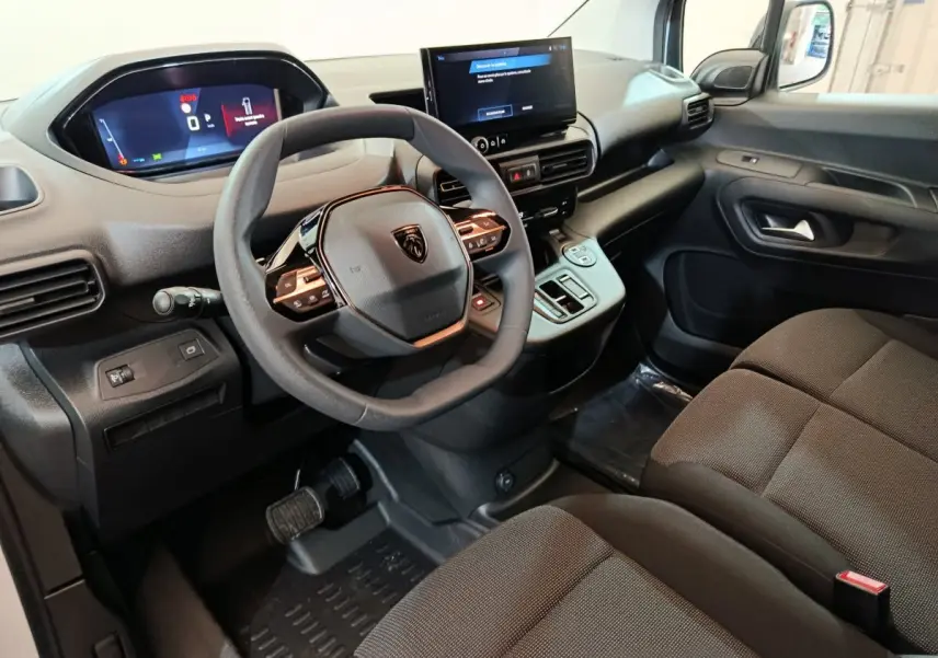 Intérieur du Peugeot Partner XL 2025 vu côté conducteur, tableau de bord moderne avec écran tactile et volant multifonction noir.