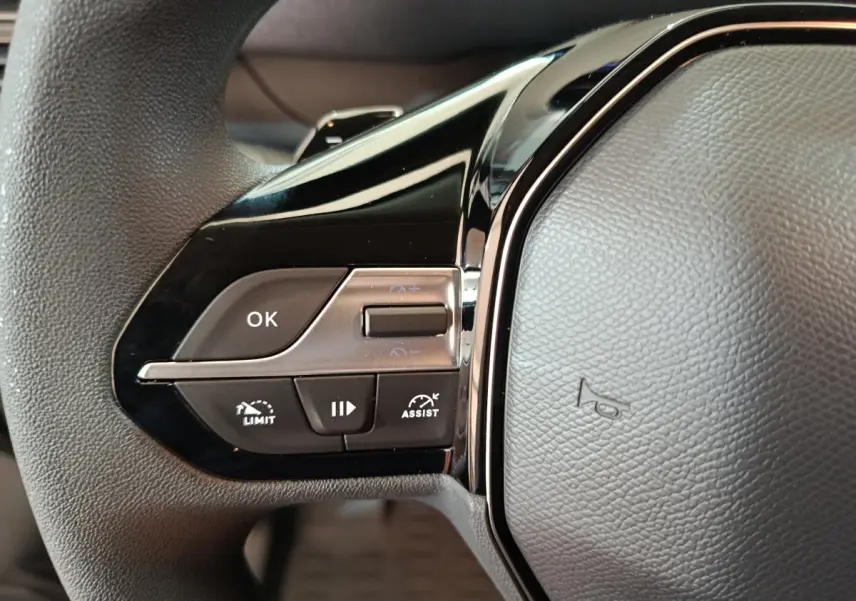 Gros plan sur les commandes gauche du volant noir du Peugeot Partner XL blanc 2025 avec boutons multifonctions.