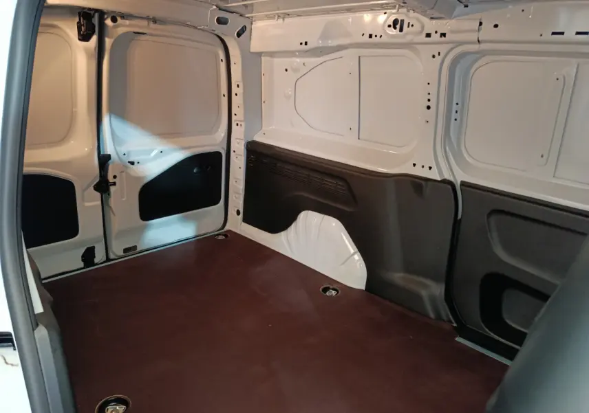 Intérieur du coffre blanc du Peugeot Partner XL 950kg vu de l'arrière gauche, montrant l'espace de chargement vide et les protections noires.