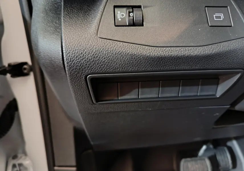 Détail du tableau de bord noir du Peugeot Partner XL 2025, avec commandes d'éclairage et boutons vides visibles.