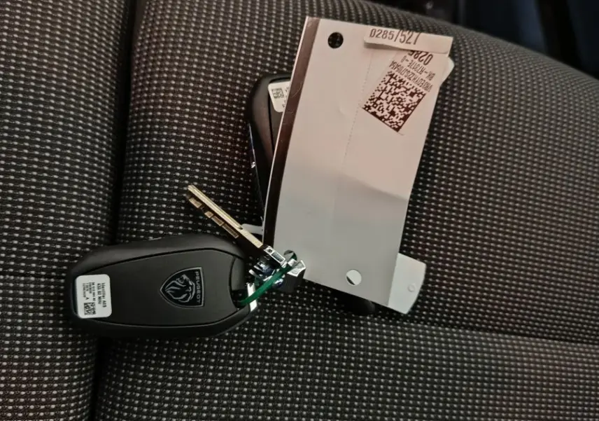 Clé Peugeot posée sur un siège avant gris à motifs, intérieur du Peugeot Partner XL 2025 visible en arrière-plan.