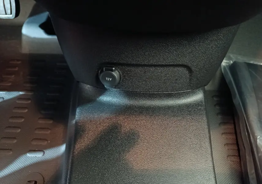 Prise 12V en gros plan sous le tableau de bord du Peugeot Partner XL blanc, intérieur noir texturé.