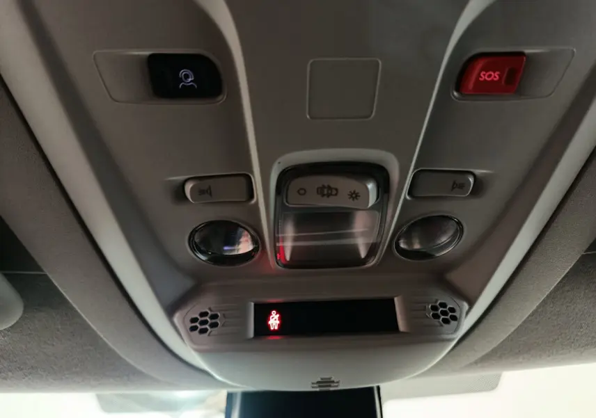 Vue en gros plan du panneau de commande au plafond intérieur du Peugeot Partner blanc, avec bouton SOS rouge et éclairage intégré.