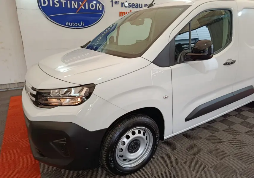 Vue 3/4 avant droit d'un Peugeot Partner XL blanc avec phares halogènes et jantes acier en intérieur showroom.