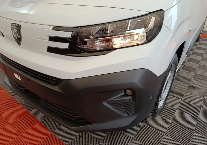 Gros plan sur le phare avant droit et la calandre noire du Peugeot Partner XL blanc, avec pare-chocs noir mat.