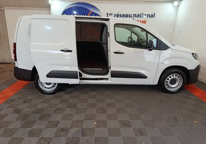 Vue de profil côté droit d’un Peugeot Partner blanc 2025 avec porte latérale coulissante ouverte montrant l’espace de chargement.