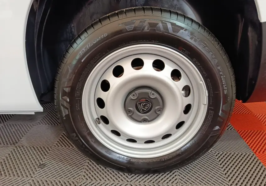 Gros plan sur la roue avant droite du Peugeot Partner blanc 2025, mettant en valeur la jante acier et le pneu Vava.