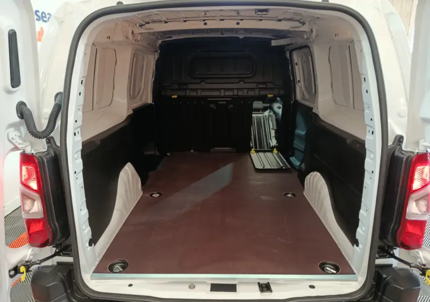 Vue arrière ouverte du Peugeot Partner XL blanc montrant l'espace de chargement vide avec plancher plat et cloison pleine noire.