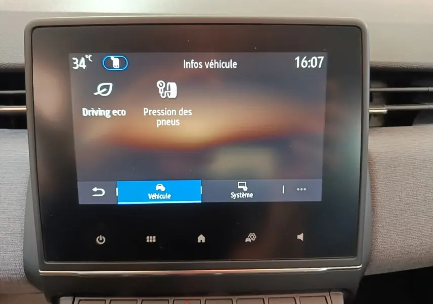 Écran tactile central affichant les infos véhicule dans l’habitacle d’une Renault Clio gris clair, vue de face.