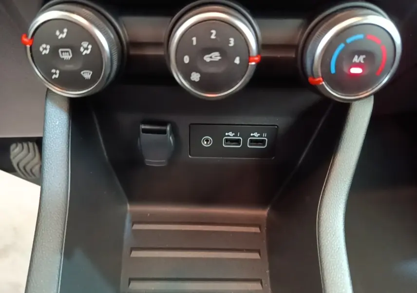 Vue rapprochée du tableau de bord de la Renault Clio gris clair 2025, montrant les commandes de climatisation et ports USB.