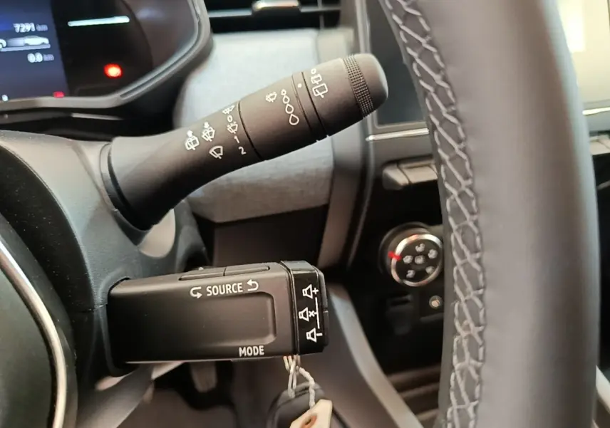 Gros plan sur la commande multifonctions noire à gauche du volant cuir synthétique dans l’habitacle gris de la Renault Clio 2025.