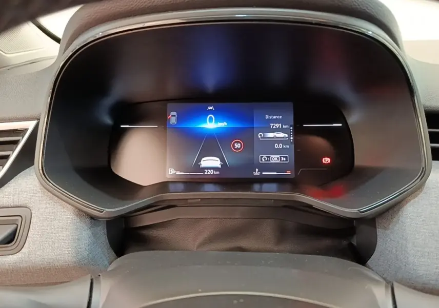 Vue rapprochée du combiné d'instruments numérique de la Renault Clio gris clair, affichant la vitesse et l'assistance à la conduite.