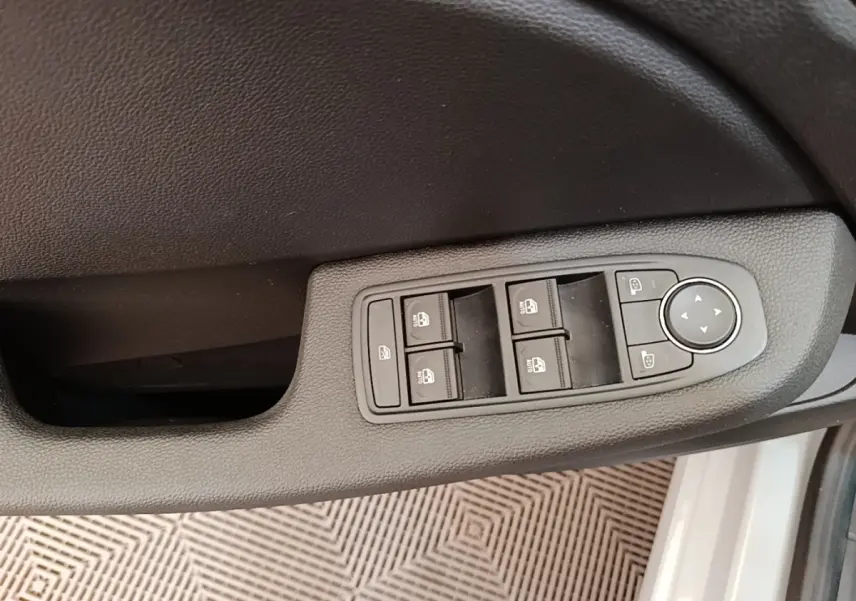 Gros plan sur la commande des vitres et rétroviseurs côté conducteur de la Renault Clio gris clair 2025.
