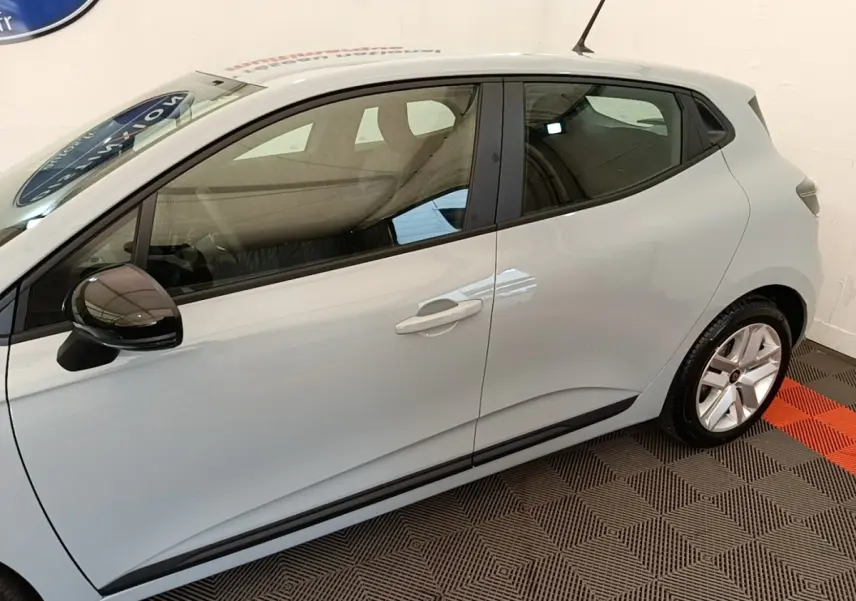 Vue de profil côté gauche d'une Renault Clio gris clair avec rétroviseur noir et jantes alliage.
