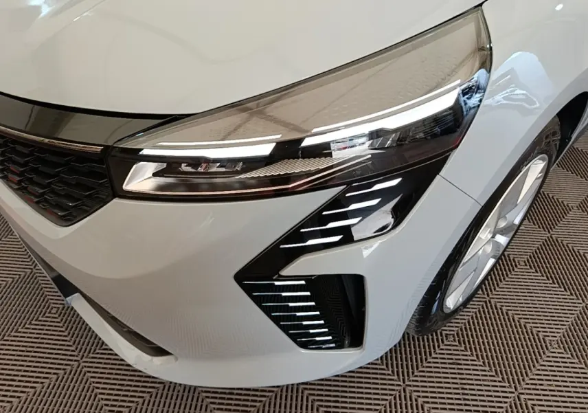 Gros plan sur l'avant droit gris clair de la Renault Clio 2025, mettant en valeur le phare LED et la calandre noire.
