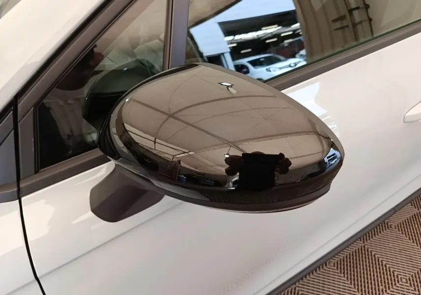 Rétroviseur extérieur noir brillant côté conducteur d'une Renault Clio gris clair, vue rapprochée en intérieur.