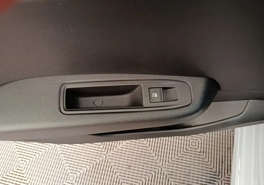 Gros plan sur la commande de verrouillage des portes côté conducteur d’une Renault Clio gris clair, intérieur noir.