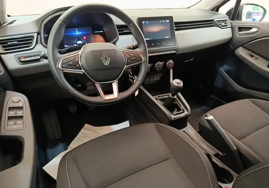 Vue intérieure avant de la Renault Clio gris clair 2025, volant cuir multifonctions et écran tactile central.