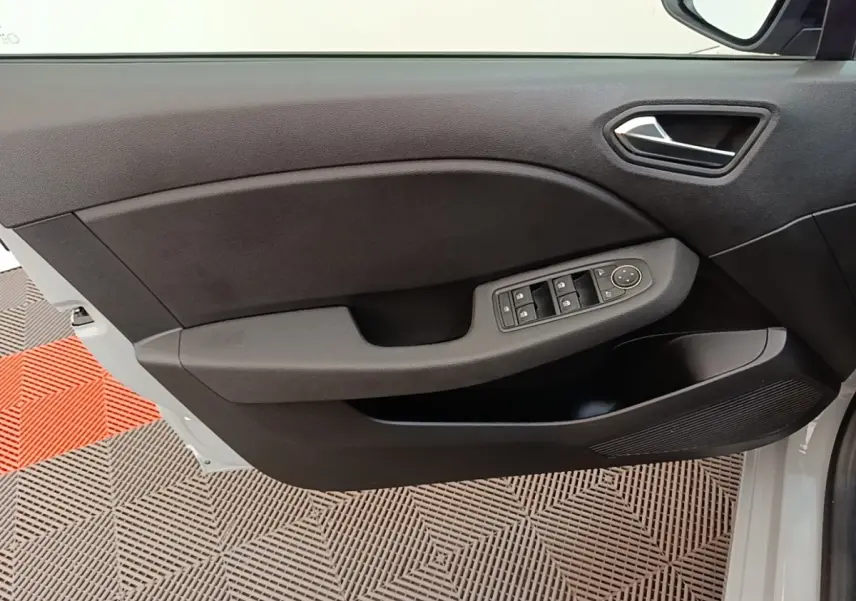 Gros plan sur la porte avant gauche de la Renault Clio gris clair, montrant les commandes des vitres et le revêtement noir.