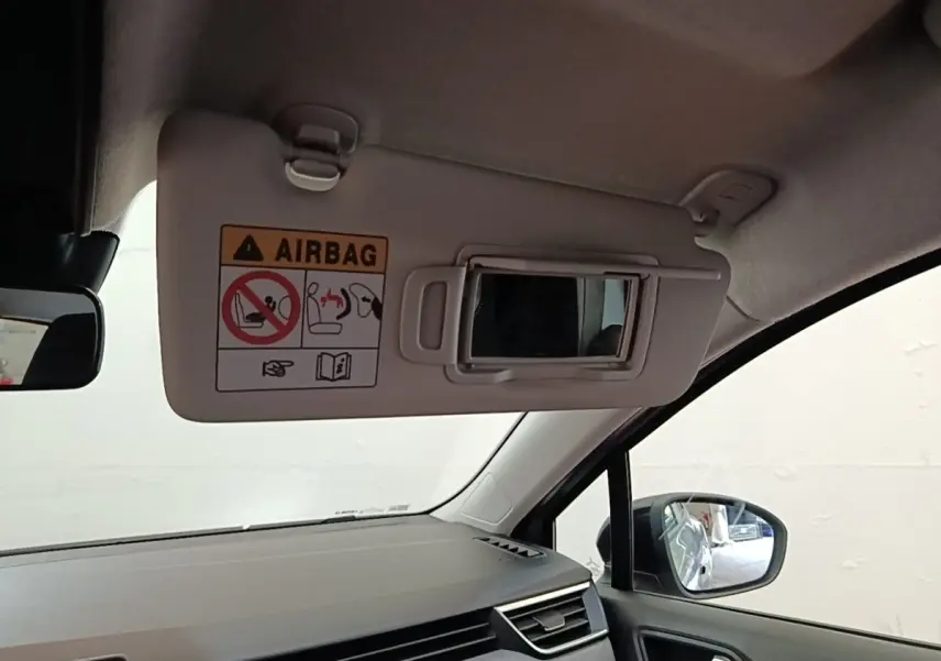 Intérieur de la Renault Clio gris clair, vue côté passager avec pare-soleil ouvert et miroir intégré.