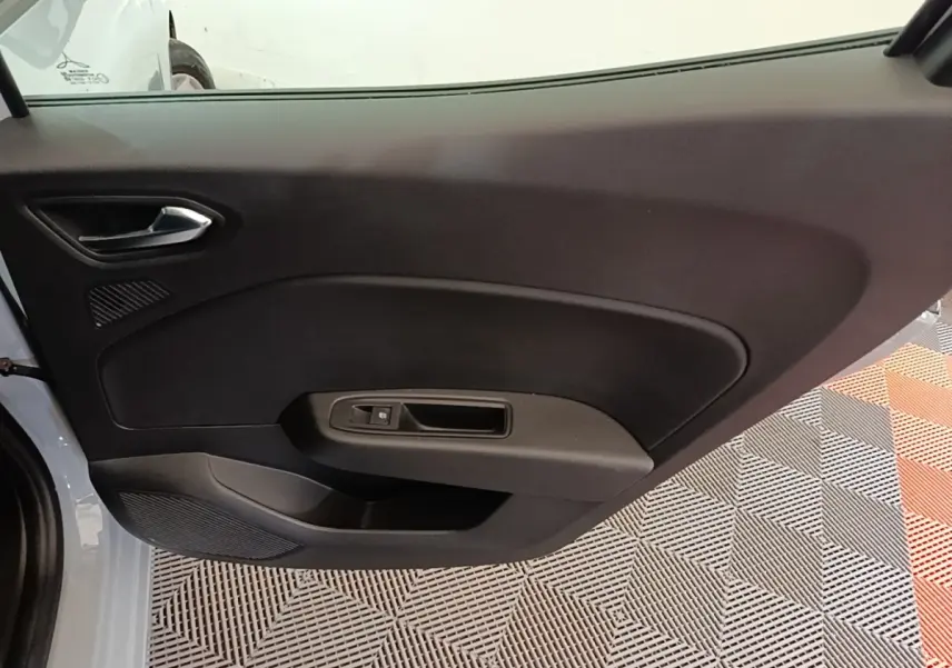 Vue intérieure du panneau de porte côté gauche de la Renault Clio gris clair, avec poignée et commande de fenêtre électrique.