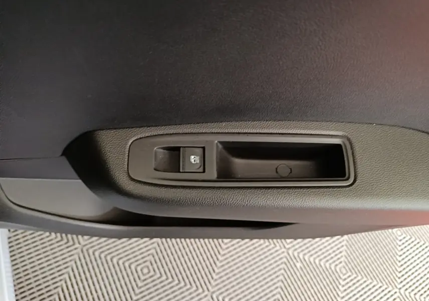 Gros plan sur la commande de verrouillage de porte côté intérieur d’une Renault Clio gris clair, version 2025.