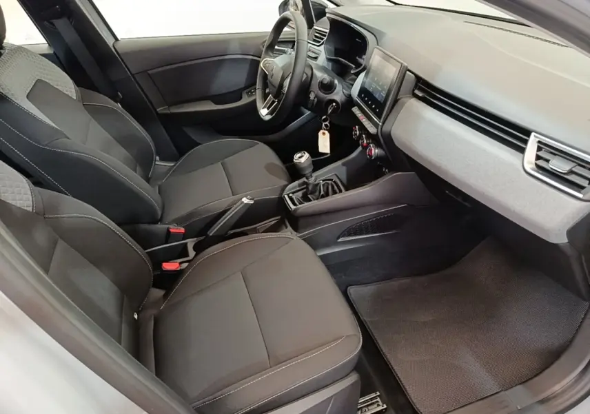 Vue intérieure côté conducteur de la Renault Clio gris clair 2025, avec sièges noirs et tableau de bord moderne.