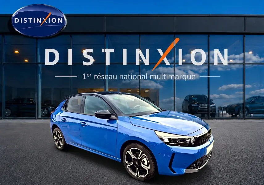Opel Corsa 1.2 turbo bleu en 3/4 avant droit, jantes alu noires et phares LED visibles devant un showroom Distinxion.