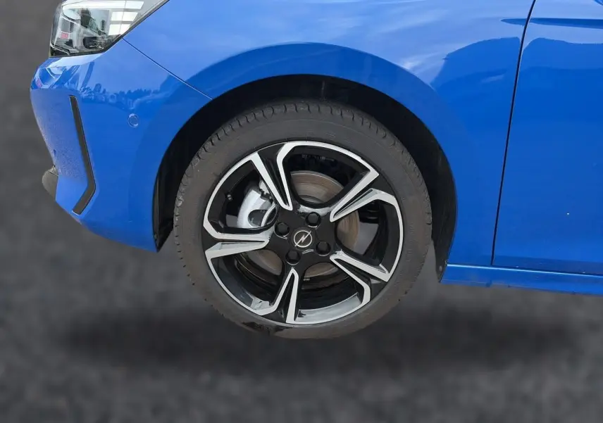 Gros plan sur la roue avant gauche et le pare-chocs bleu d'une Opel Corsa 1.2 turbo 100 GS avec jante alu noire et argent.