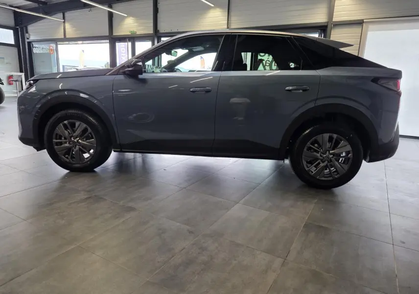 Profil côté gauche du Peugeot 3008 hybride bleu métallisé 2026 en intérieur, avec toit noir et jantes alliage.