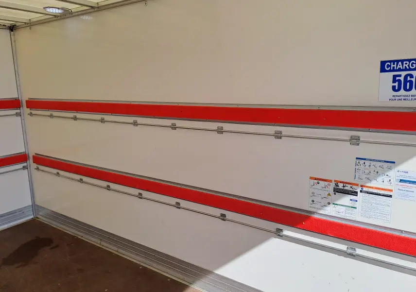 Vue intérieure du coffre blanc du Nissan Interstar Châssis Cabine 2024 avec rails rouges et panneaux d'avertissement.