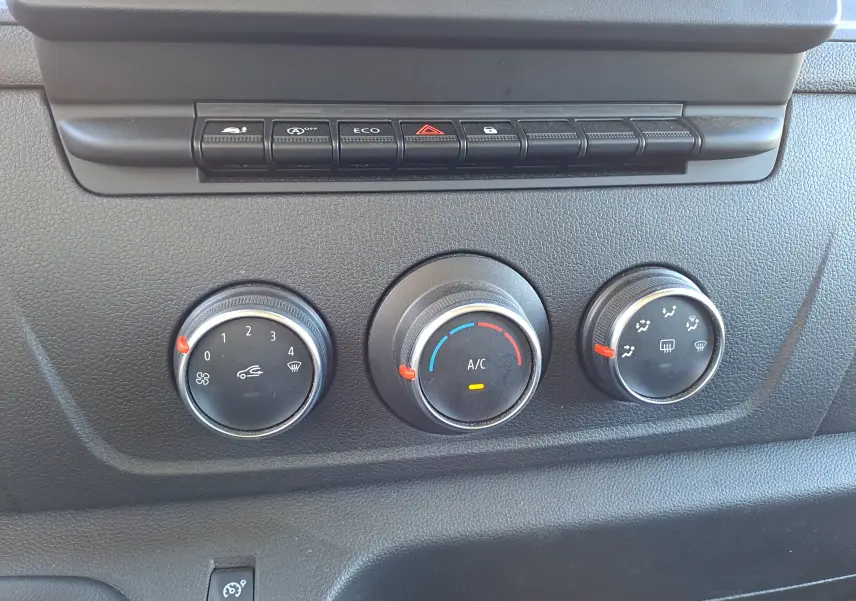 Gros plan sur les commandes de climatisation et boutons de fonction du tableau de bord du Nissan Interstar blanc 2024.