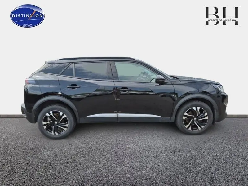 Profil droit d'un Peugeot 2008 noir Perla Nera 2021 avec jantes alu noires et barres de toit visibles.