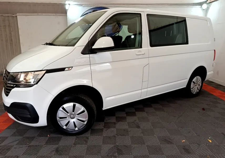Vue de profil côté gauche d'un Volkswagen Transporter blanc 2.0 TDi 150 DSG7 Business avec vitres arrière teintées.