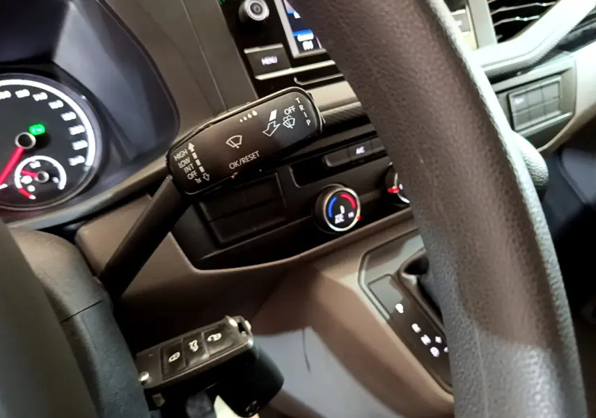 Gros plan sur le volant et la commande d'essuie-glace du Volkswagen Transporter blanc, tableau de bord et console visibles.