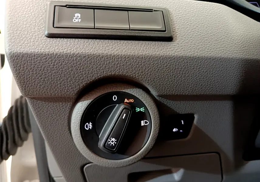 Gros plan sur le bouton de commande des phares du Volkswagen Transporter blanc, avec réglage automatique activé.