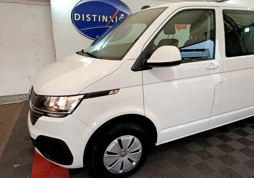 Vue 3/4 avant droite du Volkswagen Transporter blanc 2021 avec phares allumés et jantes acier.