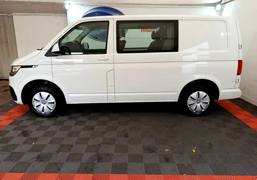 Profil côté gauche d'un Volkswagen Transporter blanc 2021, version 2.0 TDi 150 DSG7 Business en intérieur showroom.
