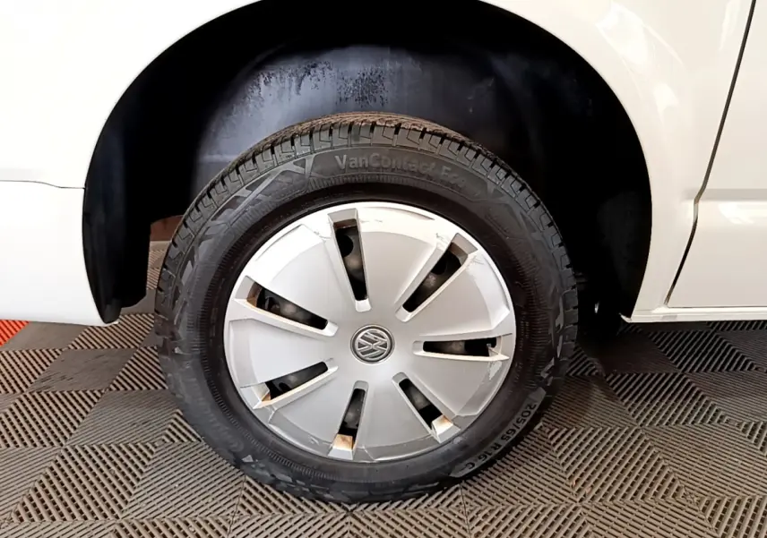 Gros plan sur la roue avant gauche blanche du Volkswagen Transporter 2.0 TDi 150 DSG7 Business avec enjoliveur d'origine.