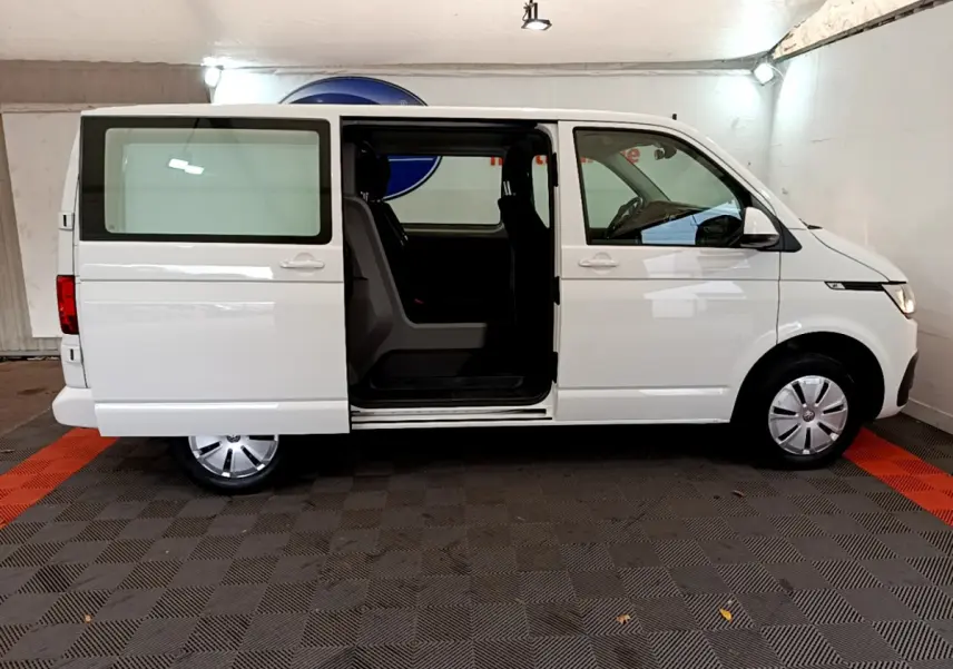 Profil droit du Volkswagen Transporter blanc 2021 avec porte coulissante ouverte dévoilant l'intérieur.