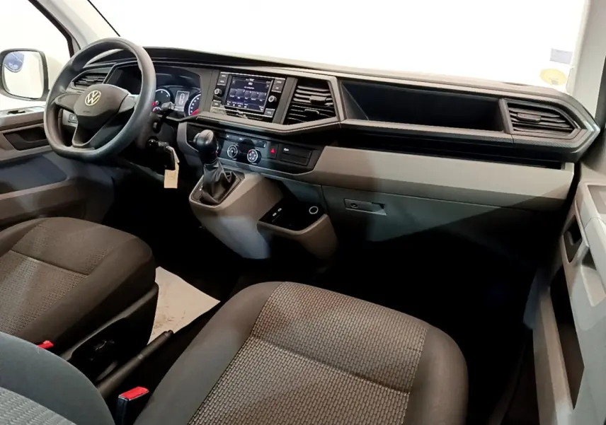 Intérieur du Volkswagen Transporter 2021, vue côté conducteur sur tableau de bord et sièges tissu gris foncé.