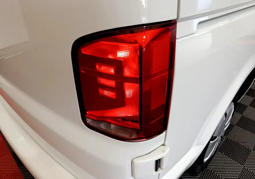 Gros plan sur le feu arrière droit du Volkswagen Transporter blanc 2021, avec partie de la carrosserie visible.