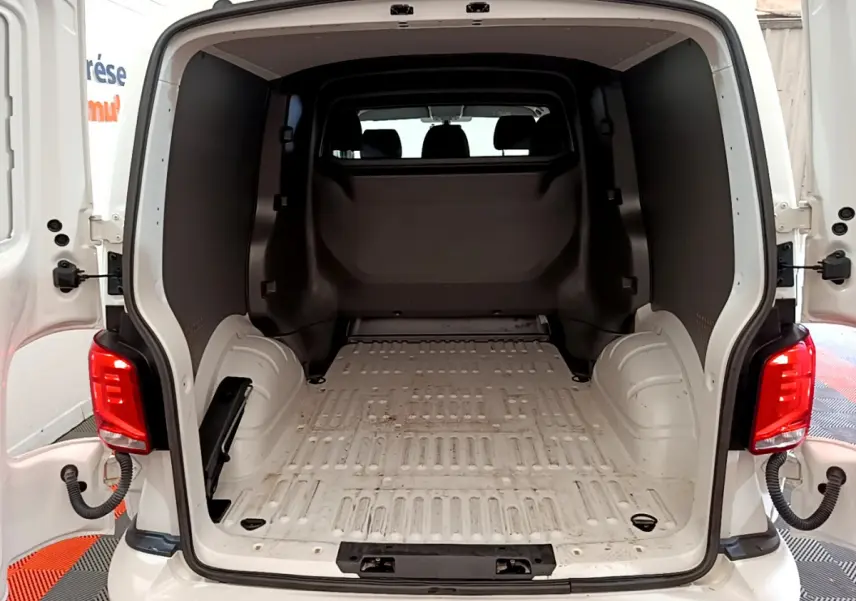 Vue arrière ouverte du Volkswagen Transporter blanc montrant l'espace de chargement vide et la cloison pleine vitrée intérieure.