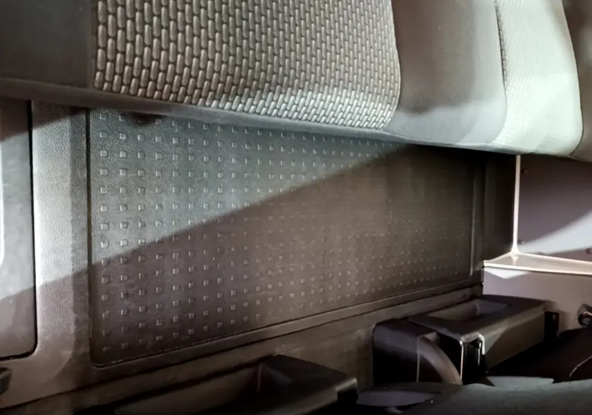 Vue intérieure du plancher arrière noir avec tapis caoutchouc et partie inférieure des sièges du Volkswagen Transporter blanc